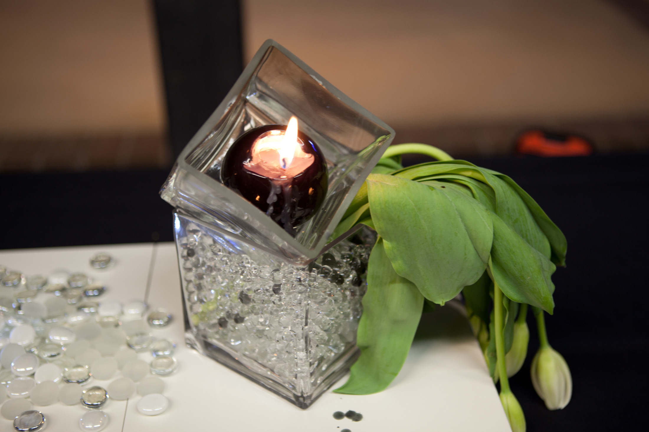 Centerpiece assembly — square cube vase with floating sphere candle, glass bead fill, and white tulips on white platform